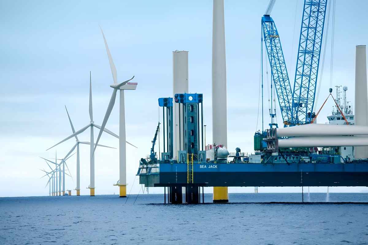Offshore wind turbines generating electricity off the U.S. coast with transmission infrastructure visible in the background
